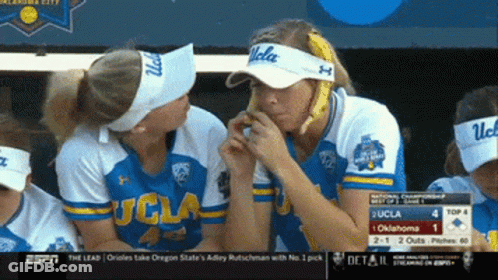 A Group Of Women Wearing Ucla Visors Are Eating Bananas GIF