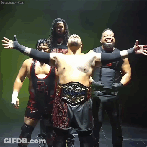 A Group Of Wrestlers Are Posing For A Photo And One Of Them Has A Belt That Says Heavyweight GIF
