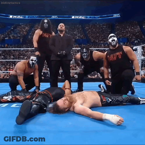 A Group Of Wrestlers Are Posing For A Picture And One Of Them Is Wearing A Black Shirt That Says Mt GIF