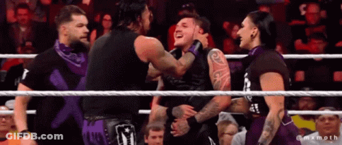 A Group Of Wrestlers Are Standing In A Ring And One Of Them Is Wearing A Shirt That Says ' X ' GIF