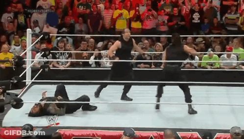 A Group Of Wrestlers Are Standing In A Ring With A Crowd Watching . GIF