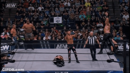 A Group Of Wrestlers Are Standing In A Ring With A Sign That Says Hey On It GIF
