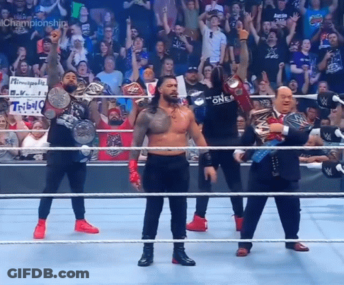 A Group Of Wrestlers Are Standing In A Ring With Their Championship Belts GIF