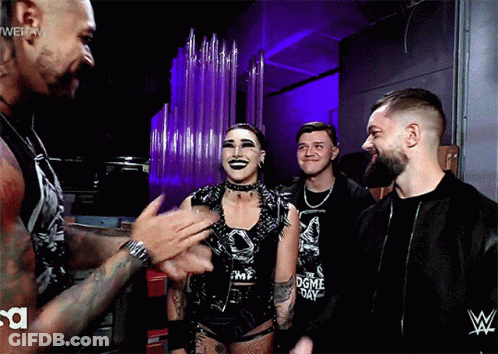 A Group Of Wrestlers Are Standing In A Room With A WWE Logo On The Wall GIF