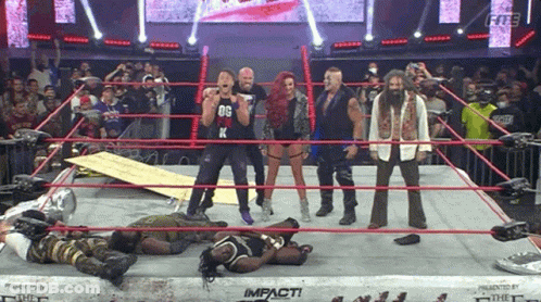 A Group Of Wrestlers Are Standing In A Wrestling Ring And One Of Them Is Wearing A Black Shirt With The Letter K On It GIF
