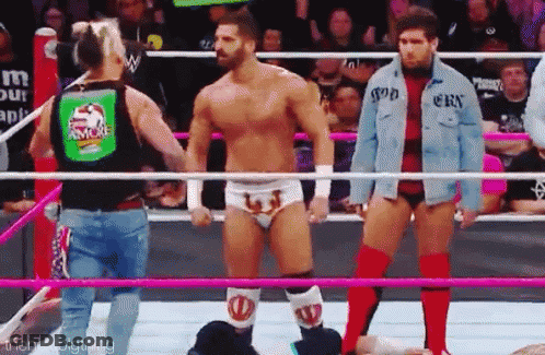 A Group Of Wrestlers Are Standing In A Wrestling Ring Holding Hands . GIF