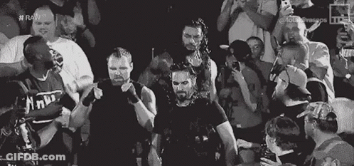 A Group Of Wrestlers Are Standing In Front Of A Crowd Of People . GIF