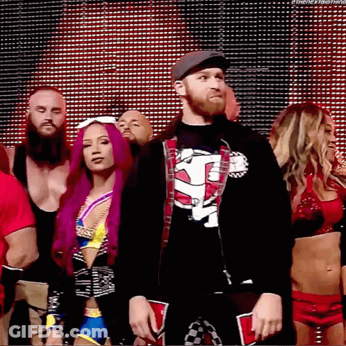 A Group Of Wrestlers Are Standing In Front Of A Large Screen And One Of Them Is Wearing A Shirt That Says Tna GIF