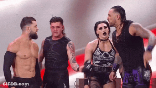 A Group Of Wrestlers Are Standing Next To Each Other And One Of Them Is Wearing A Purple Outfit GIF