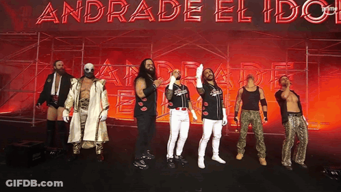 A Group Of Wrestlers Stand In Front Of A Sign That Says Andrade El Idol GIF
