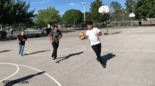 A Group Of Young Boys Are Playing Basketball On A Court GIF