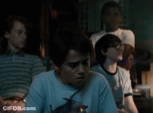 A Group Of Young Boys Are Sitting In A Dark Room And One Of Them Is Holding A Lighter . GIF