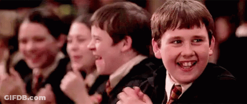 A Group Of Young Boys Are Sitting In A Row Clapping Their Hands . GIF