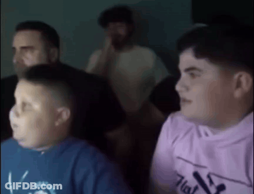 A Group Of Young Boys Are Sitting In Front Of A Screen . GIF