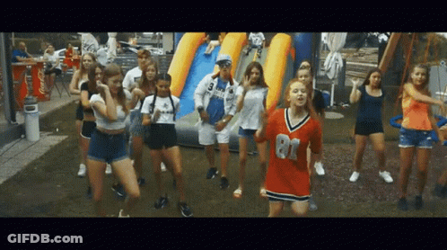 A Group Of Young Girls Are Dancing In Front Of A Coca Cola Cooler GIF