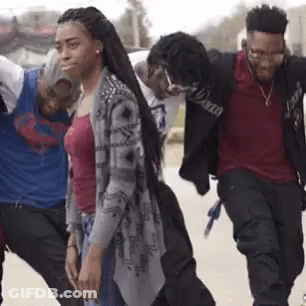 A Group Of Young Men And Women Are Walking Down The Street . GIF