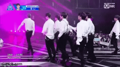 A Group Of Young Men Are Dancing On A Stage In Front Of A Crowd And A Sign That Says Mnet GIF