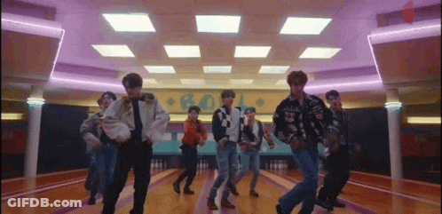 A Group Of Young Men Are Dancing Together In A Bowling Alley . GIF