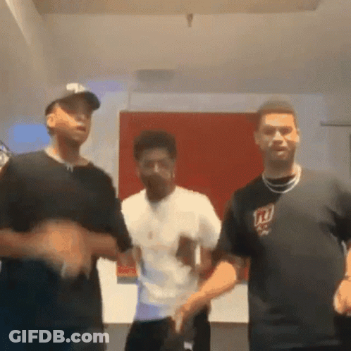 A Group Of Young Men Are Dancing Together In A Room . One Of The Men Is Wearing A Ny Giants Shirt . GIF