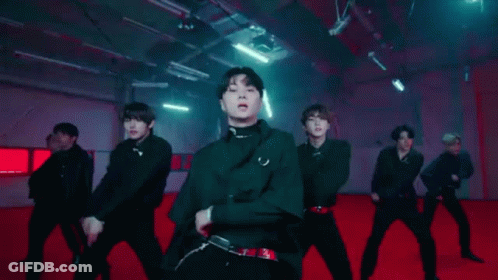 A Group Of Young Men Are Dancing Together On A Red Carpet In A Dark Room . GIF