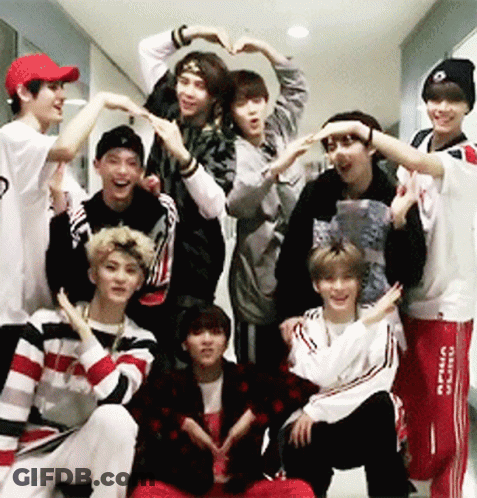 A Group Of Young Men Are Making A Heart Shape With Their Hands In A Hallway GIF