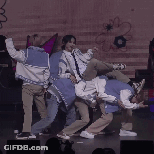 A Group Of Young Men Are Performing On A Stage With A Sign That Says Boom GIF