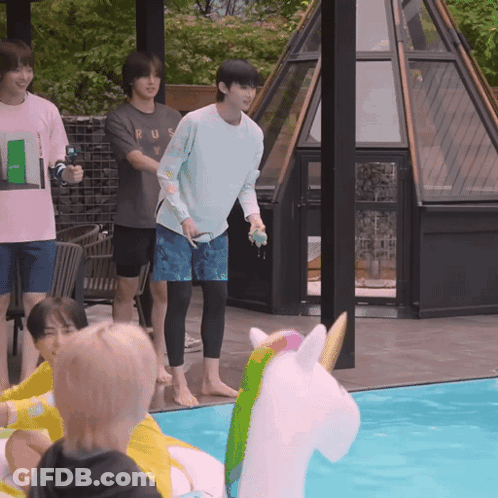 A Group Of Young Men Are Playing In A Swimming Pool With A Unicorn Float In The Middle GIF