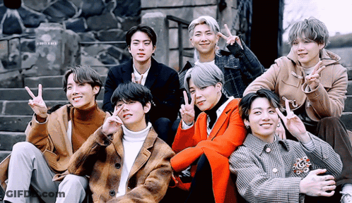 A Group Of Young Men Are Posing For A Picture While Giving Peace Signs GIF