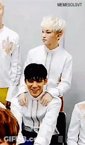 A Group Of Young Men Are Sitting In A Room And One Of Them Is Sitting On Another 'S Shoulders . GIF