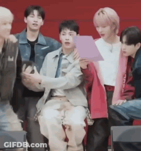 A Group Of Young Men Are Sitting In Chairs And Talking To Each Other . GIF
