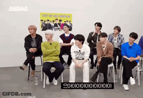 A Group Of Young Men Are Sitting In Front Of A Sign That Says Nst GIF