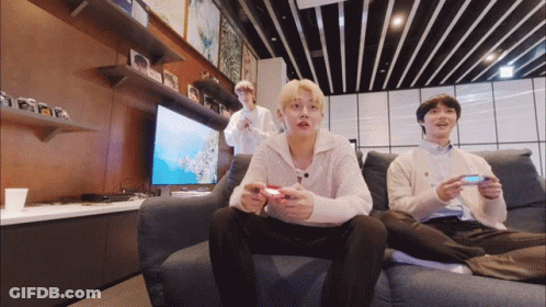 A Group Of Young Men Are Sitting On A Couch Playing Video Games GIF