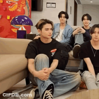 A Group Of Young Men Are Sitting On The Floor In Front Of A Couch .. GIF