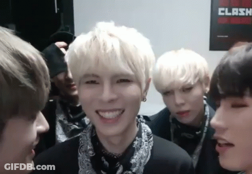 A Group Of Young Men Are Smiling In Front Of A Clash Poster On The Wall GIF