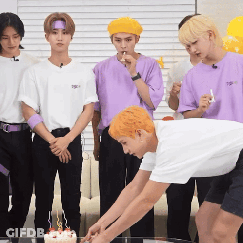 A Group Of Young Men Are Standing Around A Cake With Candles GIF