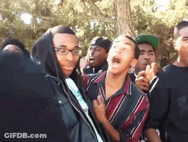 A Group Of Young Men Are Standing In A Crowd And One Of Them Is Wearing Glasses And A Hoodie . GIF