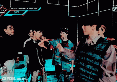 A Group Of Young Men Are Standing In A Dark Room With A Sign That Says Mcd Comeback Special Got7 GIF