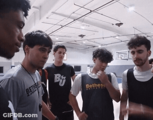 A Group Of Young Men Are Standing In A Gym And One Of Them Is Wearing A Shirt That Says Bethess University GIF