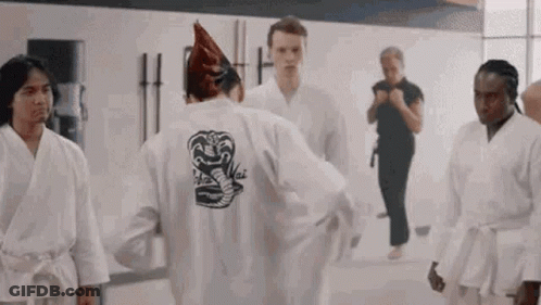 A Group Of Young Men Are Standing In A Gym Wearing Karate Uniforms . GIF