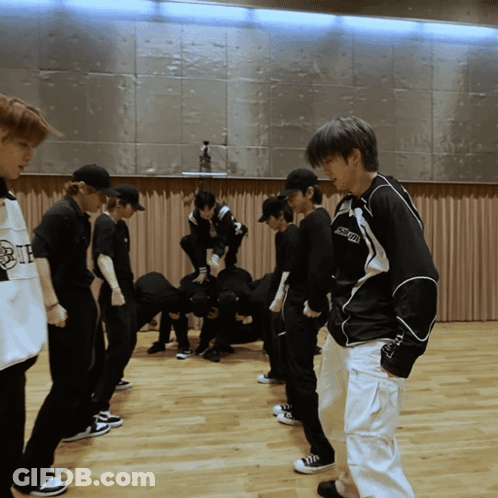 A Group Of Young Men Are Standing In A Room And One Of Them Is Wearing A Shirt That Says " Supreme " On It GIF