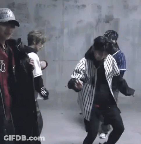 A Group Of Young Men Are Standing In A Room . GIF