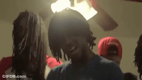 A Group Of Young Men Are Standing In A Room With A Ceiling Fan . GIF