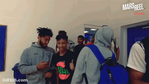 A Group Of Young Men Are Standing In A Room With A Sign That Says Mars Reel On It GIF