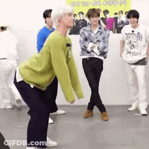 A Group Of Young Men Are Standing In A Room . GIF