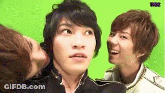 A Group Of Young Men Are Standing Next To Each Other And One Of Them Is Kissing Another Man On The Cheek . GIF
