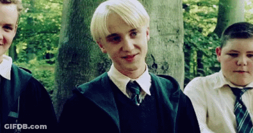 A Group Of Young Men Are Standing Next To Each Other In A Forest . One Of The Boys Is Wearing A Green Tie . GIF