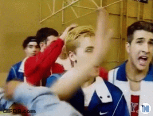 A Group Of Young Men Are Standing Next To Each Other In A Gym And One Of Them Is Yelling . GIF
