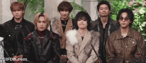 A Group Of Young Men Are Standing Next To Each Other In A Line . GIF