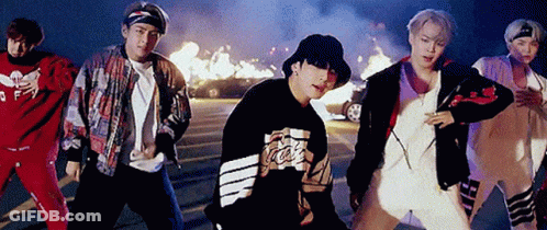 A Group Of Young Men Are Standing Next To Each Other In A Parking Lot In Front Of A Fire . GIF