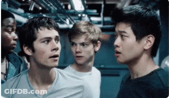 A Group Of Young Men Are Standing Next To Each Other In A Room Looking At Something . GIF